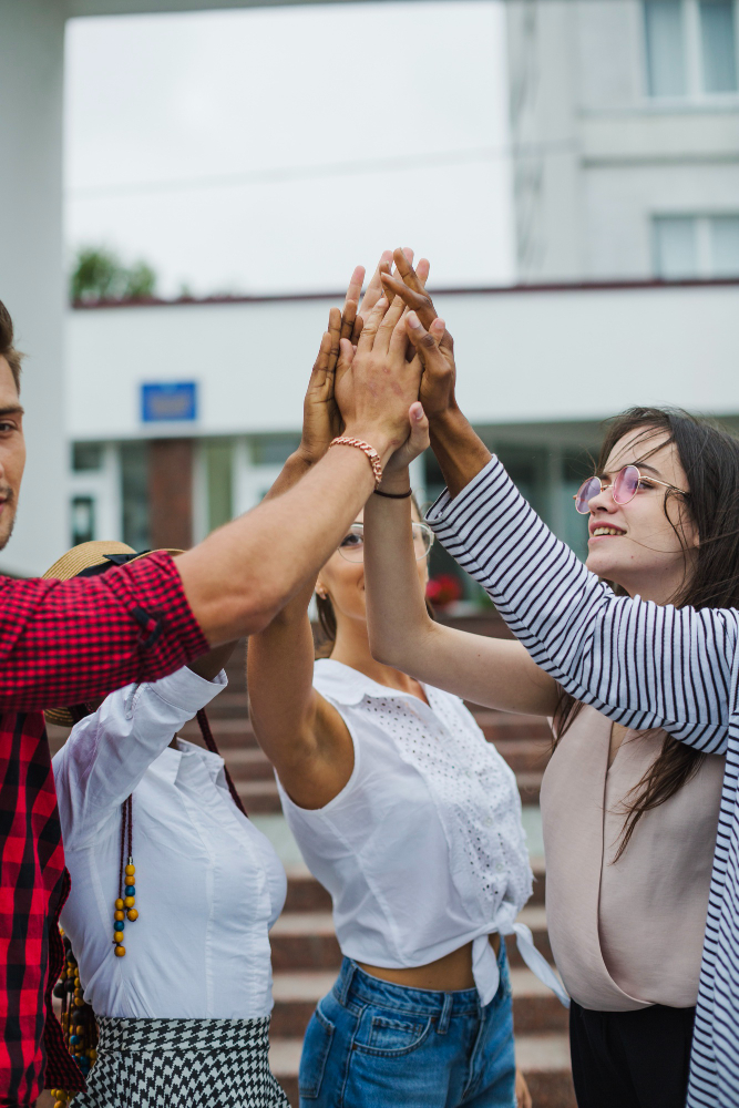 Students giving a high-five, celebrating teamwork outdoors.